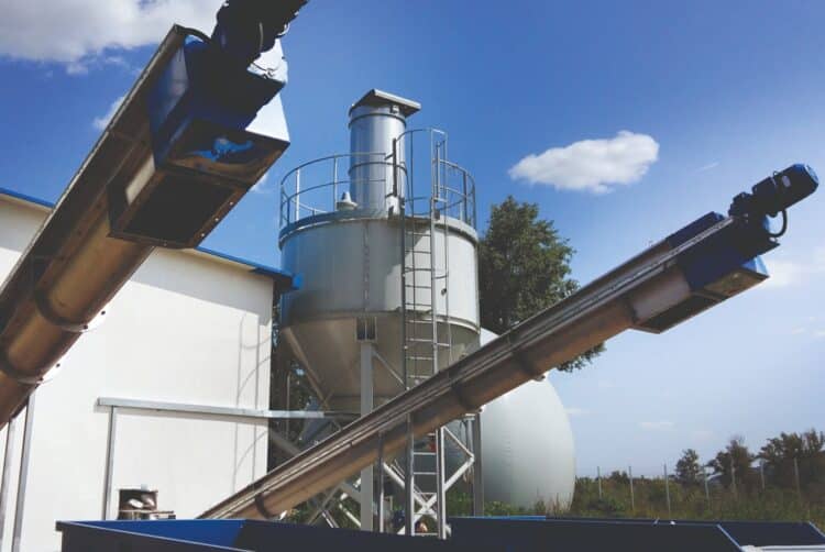 SAVECO’s shaftless screw conveyors with silo discharging in the background. Image: WAMGROUP.